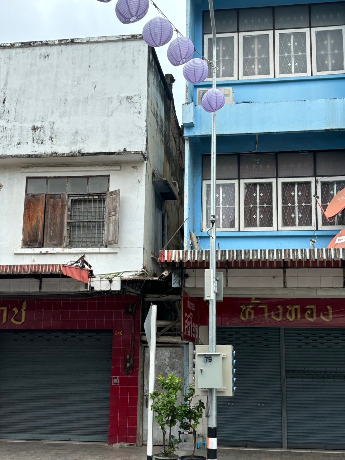 Photocontrol assembly on a metal pole outside a blue building in Chiang Rai, Thailand.