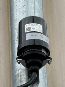 Close-up of a photocontrol and mating receptacle assembly secured to a metal pole in Chiang Rai, Thailand.