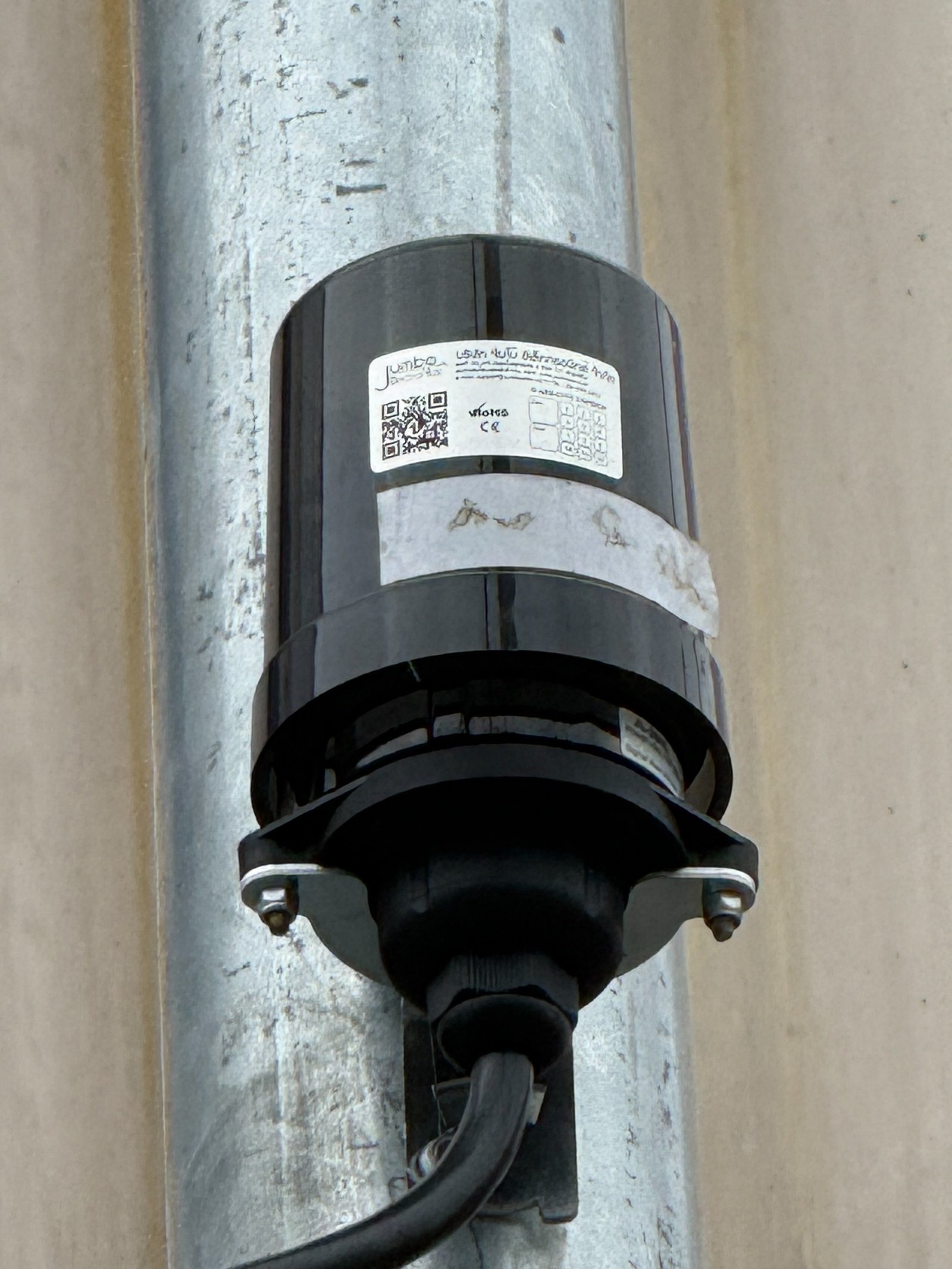 Close-up of a photocontrol and mating receptacle assembly secured to a metal pole in Chiang Rai, Thailand.